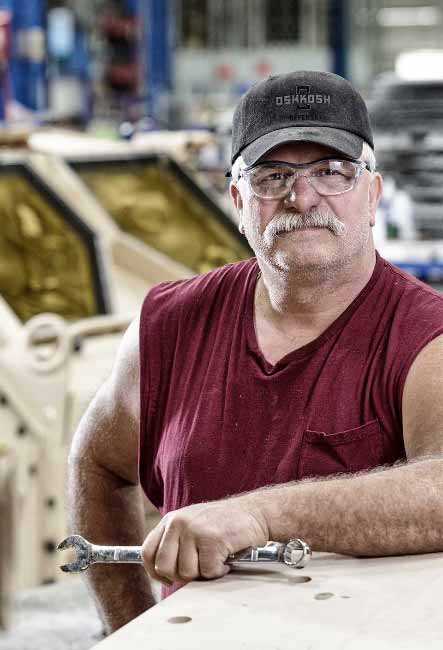 Oshkosh Defense employee holding wrench at work