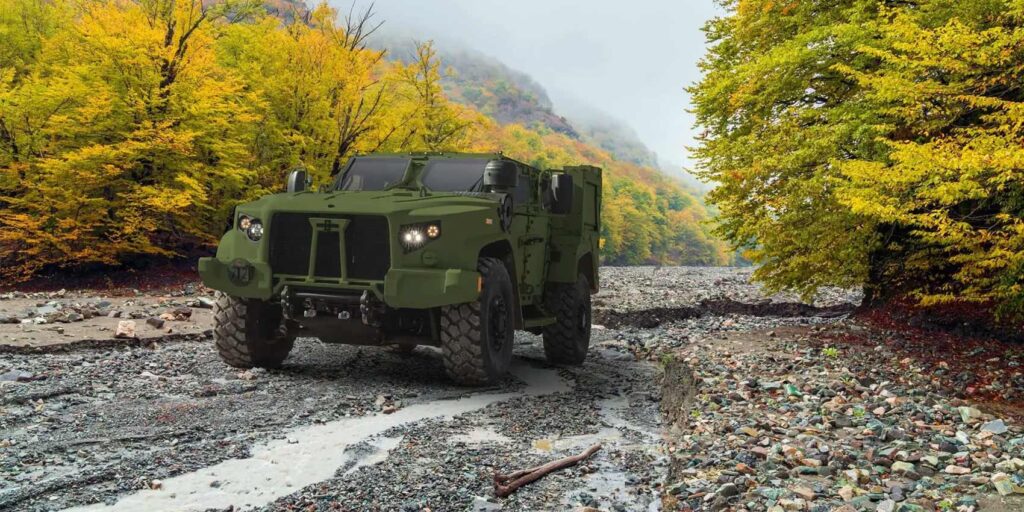 JLTV military vehicle driving on a rough road in the fall.