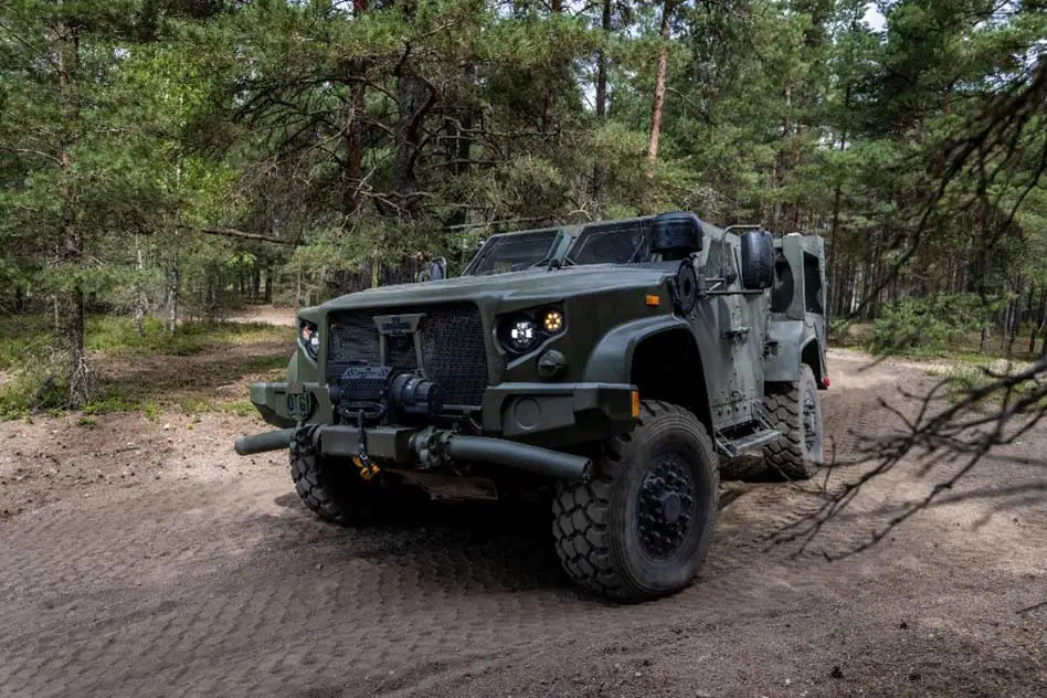 Oshkosh Defense JLTV driving on rough terrain in a wooded area.