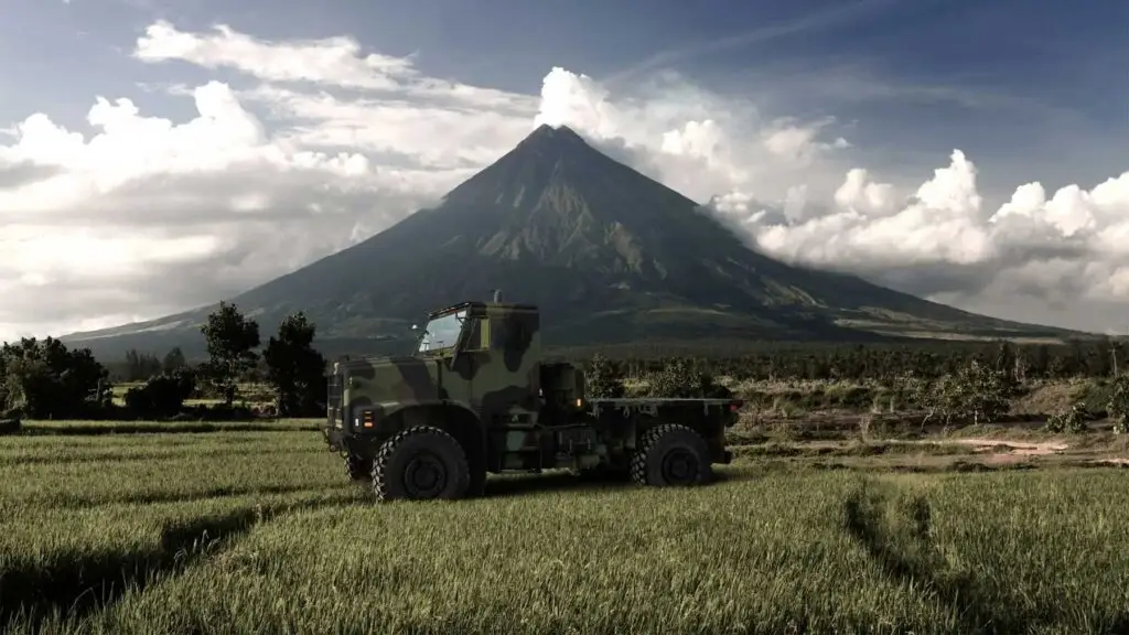 Oshkosh Defense MVTR tactical vehicle in a field with a mountain in the background.