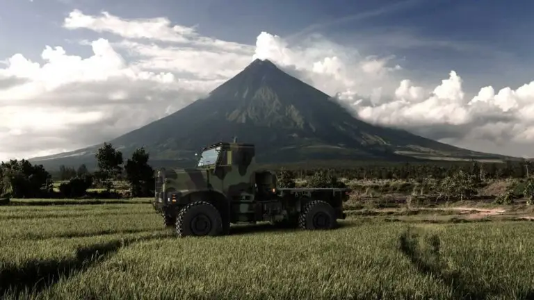 Oshkosh Defense MVTR tactical vehicle in a field with a mountain in the background.