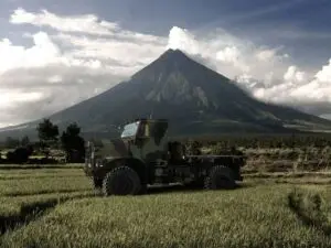 Oshkosh Defense MVTR tactical vehicle in a field with a mountain in the background.