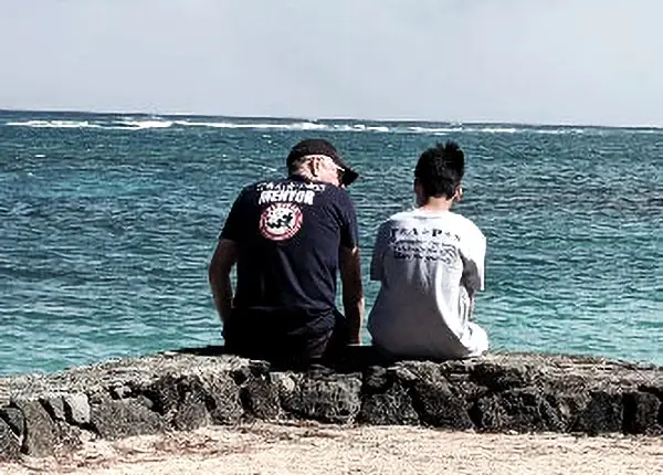 Two people sitting by the ocean.