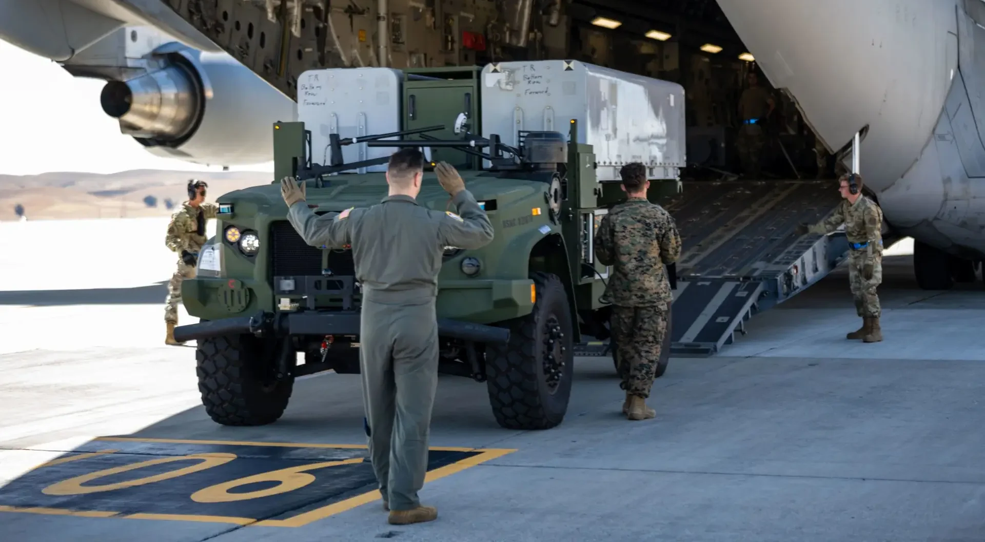 An Oshkosh Defense ROGUE-FIRES being loaded into an aircraft carrier for transport