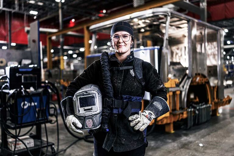 A welder holding a helmet at Oshkosh Defense.